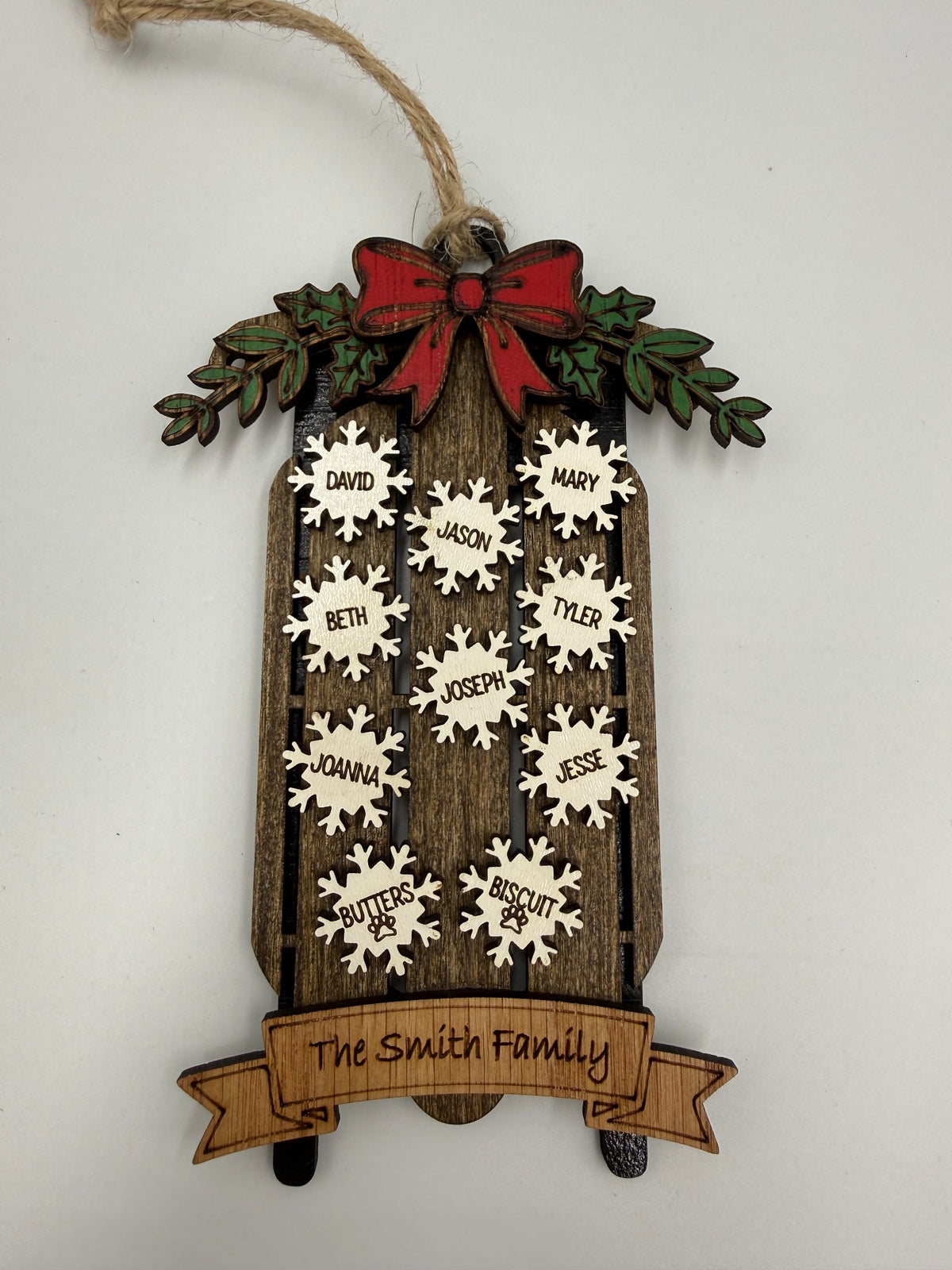 Personalized family sled ornament showing layered wood construction and name snowflakes