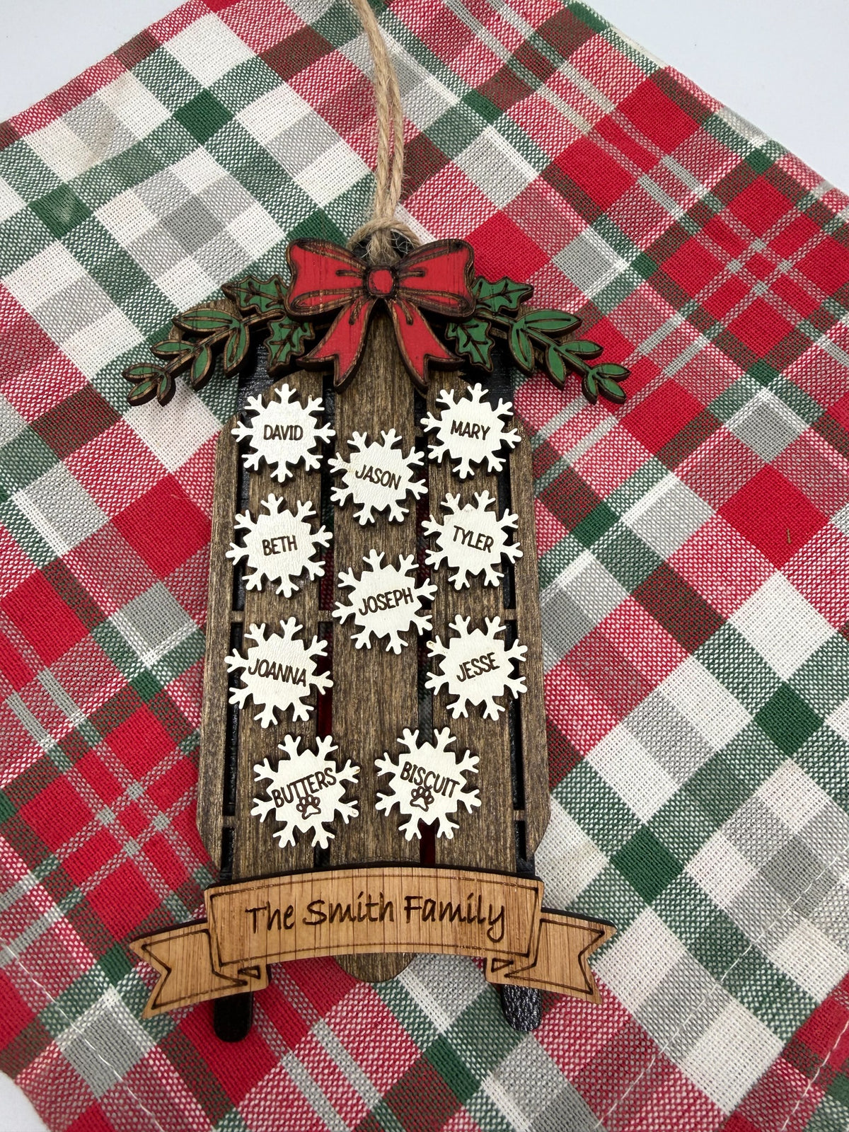 Personalized family sled ornament displayed on Christmas plaid fabric